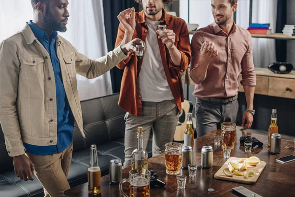 Recortado disparo de multiétnicos amigos varones beber alcohol juntos - foto de stock