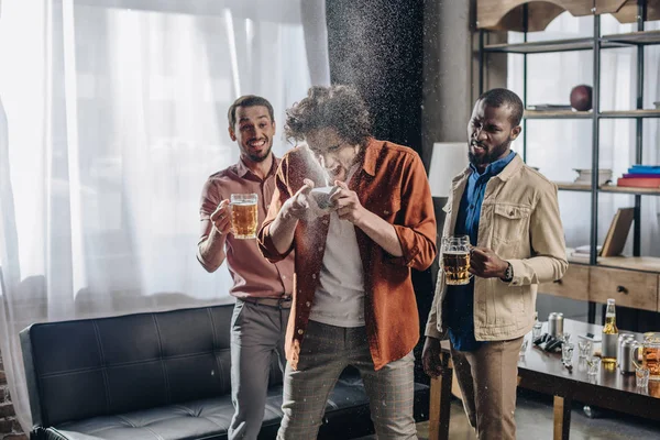 Rindo amigos multiétnicos olhando para o homem bebendo cerveja de lata — Fotografia de Stock