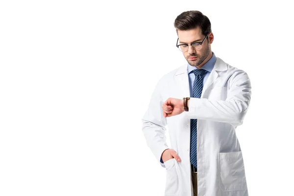 Médico varón vistiendo bata blanca revisando su reloj aislado en blanco - foto de stock