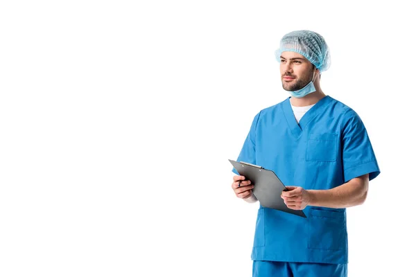 Surgeon wearing blue uniform and writing diagnosis in clipboard isolated on white — Stock Photo