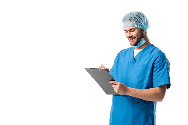 Cheerful surgeon  wearing blue uniform and holding clipboard isolated on white — Stock Photo