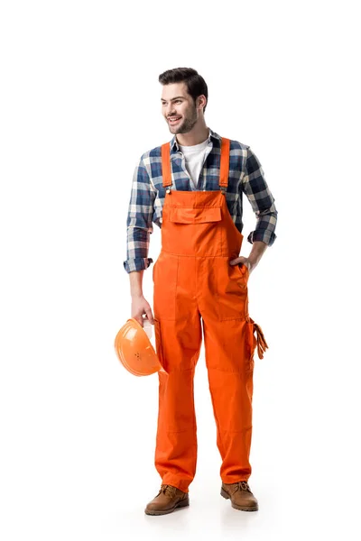 Jovem construtor em laranja geral segurando chapéu duro isolado no branco — Fotografia de Stock