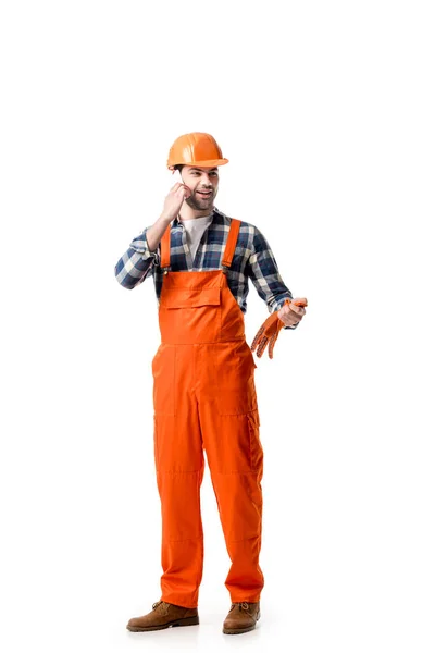 Young repairman in orange overall and hard hat talking on the phone isolated on white — Stock Photo