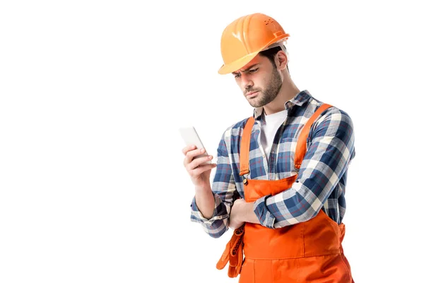 Workman in orange overall and hard hat using smartphone isolated on white — Stock Photo