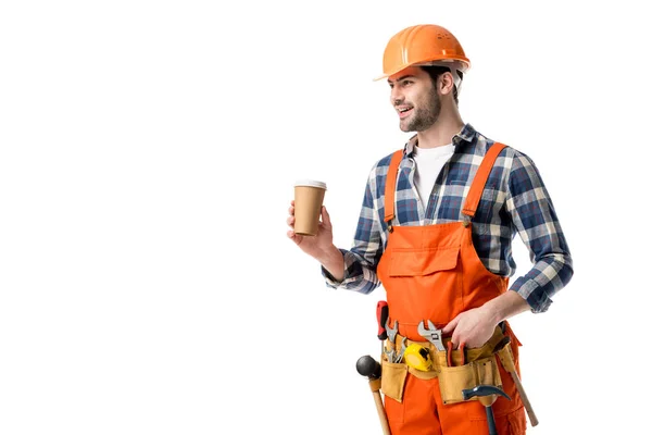 Construtor sorridente em laranja geral e cinto de ferramentas beber café isolado em branco — Fotografia de Stock