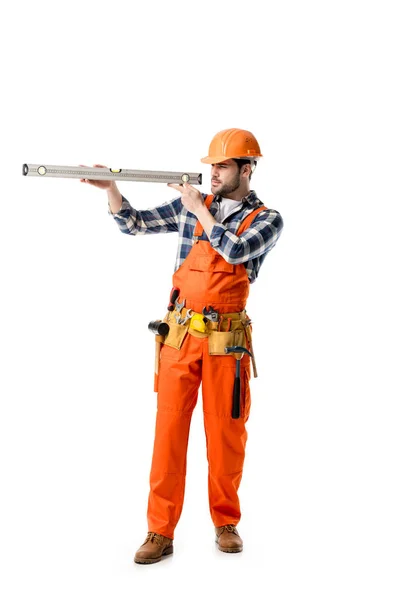 Ouvrier en orange général et casque dur vérifiant le niveau d'esprit isolé sur blanc — Photo de stock