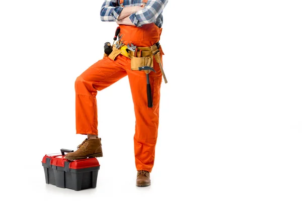 Cropped view of workman in orange overall leaning on tool box isolated on white — Stock Photo