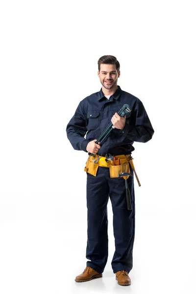 Confident handyman wearing uniform with tool belt and holding wrench isolated on white — Stock Photo
