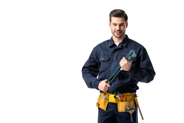 Smiling reparador vestindo uniforme com cinto de ferramentas e segurando chave isolada no branco — Fotografia de Stock