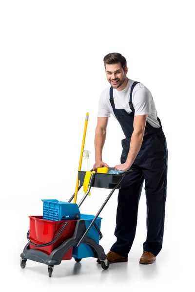 Limpiador sonriente en uniforme con carro aislado en blanco - foto de stock