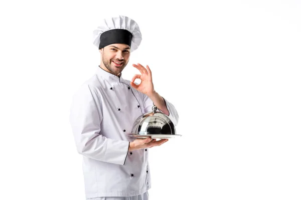 Chef sonriente con bandeja de servir mostrando signo ok aislado en blanco - foto de stock