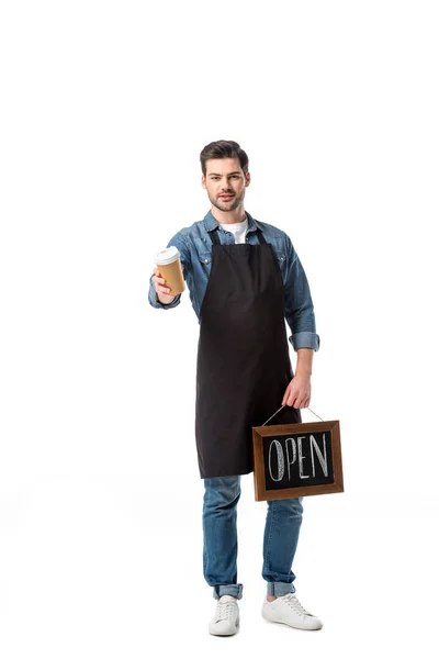 Young waiter in apron with open blackboard and coffee to go isolated on white — Stock Photo