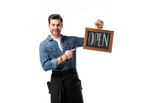 Портрет улыбающегося официанта, указывающего на открытую доску в руке, изолированную на белом — стоковое фото