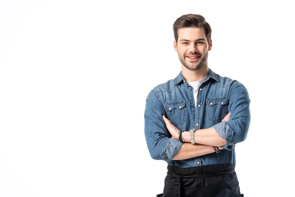 Portrait of smiling waiter in apron with arms crossed isolated on white — Stock Photo