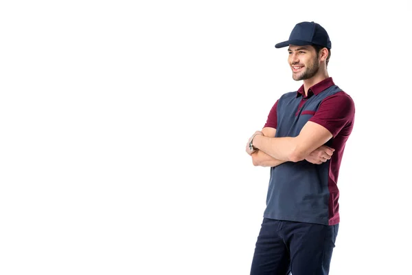 Vista lateral del repartidor sonriente en gorra con los brazos cruzados aislados en blanco - foto de stock