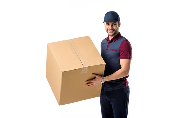 Vista laterale di uomo consegna sorridente in tappo con scatola di cartone in mani isolate su bianco — Foto stock