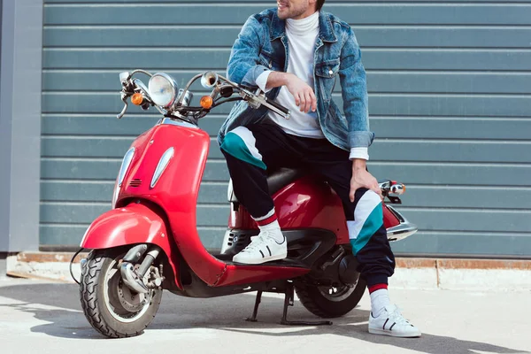 Cropped shot of young man in denim jacket on vintage red scooter — Stock Photo