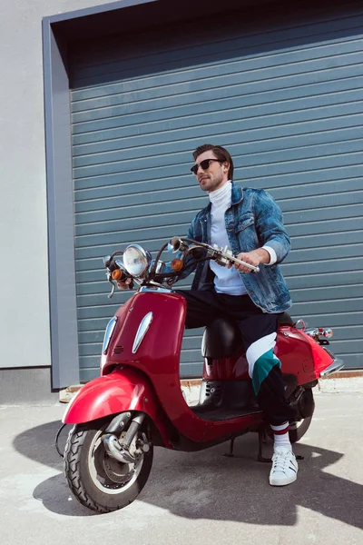 Stylish young man in denim jacket on vintage red scooter — Stock Photo