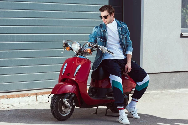 Beau jeune homme en vêtements vintage élégant assis sur scooter — Photo de stock