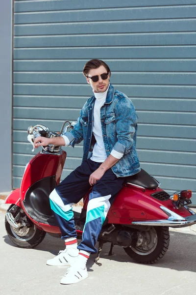 Молодий чоловік у стильному вінтажному одязі, що сидить на скутері — стокове фото
