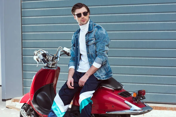 Young man in stylish vintage clothes sitting on scooter and looking away — Stock Photo