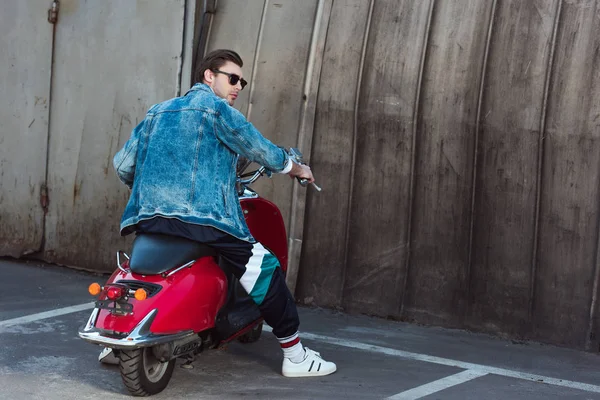 Jeune homme en jean veste élégante avec scooter vintage sur le parking — Photo de stock