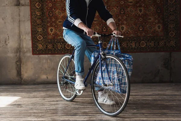 Cropped shot of man in vintage clothes on road bike in front of rug hanging on wall — Stock Photo