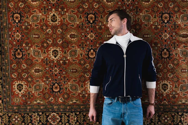 Beau jeune homme en vêtements vintage tapis couché — Photo de stock