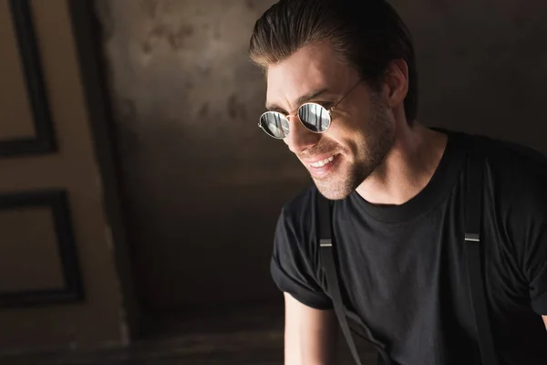 Retrato de cerca del joven sonriente en camiseta negra y gafas de sol - foto de stock