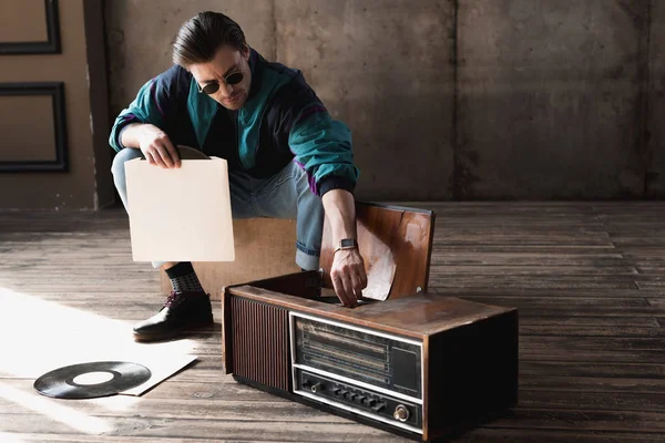 Bell'uomo nostalgico in giacca a vento vintage con giradischi in vinile — Foto stock