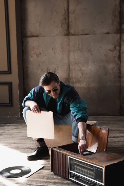 Smiling young man in vintage windcheater with vinyl record player — Stock Photo