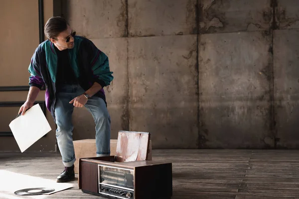 Joven con estilo en la vendimia windcheater con reproductor de discos de vinilo - foto de stock