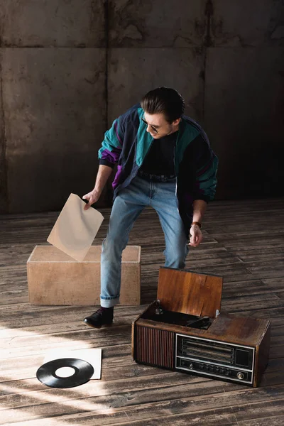 Hombre nostálgico en cazadora de viento vintage con tocadiscos de vinilo - foto de stock