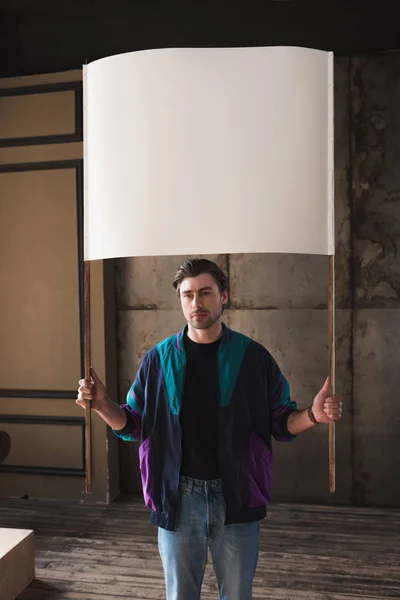 Serious young man in vintage windcheater with blank placard — Stock Photo