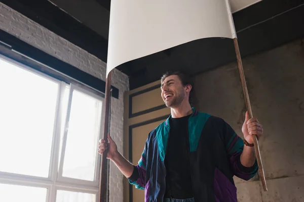 Smiling young man in vintage windcheater with blank placard — Stock Photo