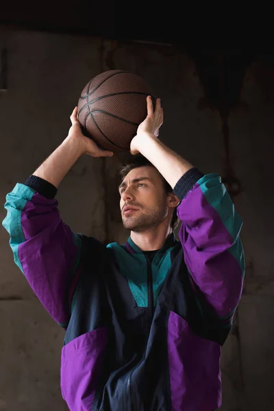 Joven con estilo en la vendimia windcheater lanzar pelota de baloncesto - foto de stock