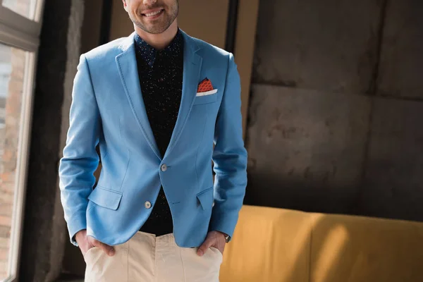 Recortado disparo de sonriente joven en elegante chaqueta azul en el interior del loft - foto de stock