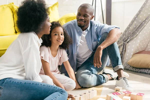 Sorridente africano americano seduto sul pavimento insieme a casa — Foto stock