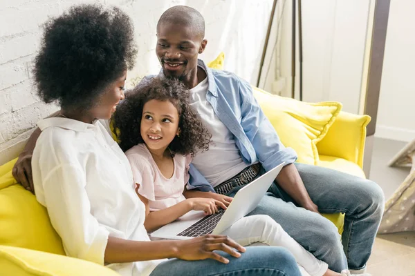 African american family with laptop resting on sofa together at home — Stock Photo