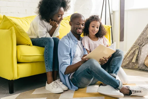 Glücklich afrikanisch-amerikanische Familie liest Buch zusammen zu Hause — Stockfoto