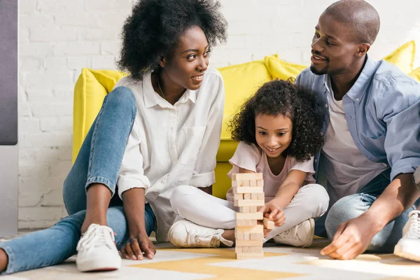 Афро-американські батьки і дочка грають блоки вежі разом вдома — стокове фото