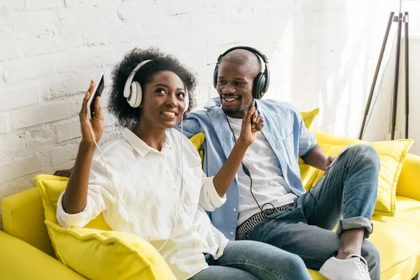 Афроамериканська прослуховування музики в навушниках, відпочиваючи на дивані вдома — Stock Photo