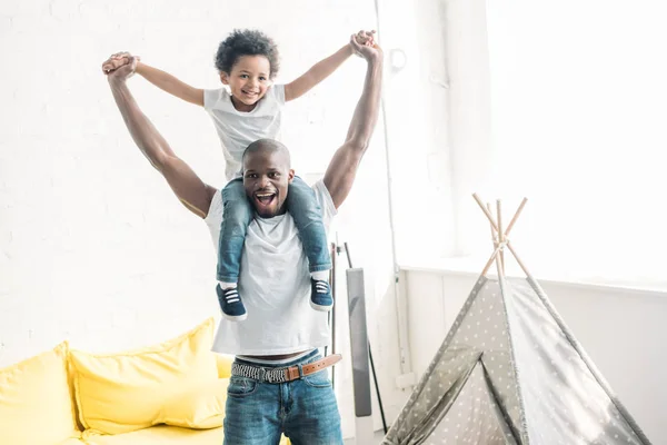 Glücklich afrikanisch-amerikanischer Mann spielt mit kleinem Sohn zu Hause — Stockfoto