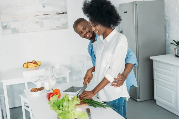 Sonriente afroamericano cocina desayuno juntos en cocina en casa - foto de stock