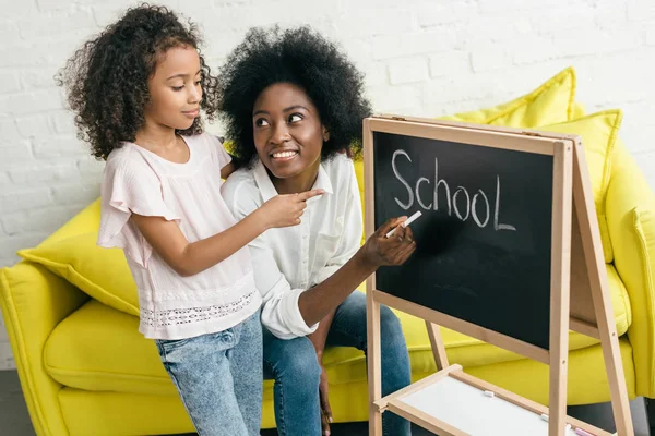 Mulher afro-americana estudando junto com a filha em casa — Fotografia de Stock