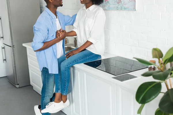 Vista parcial de pareja afroamericana cogida de la mano en la cocina en casa - foto de stock