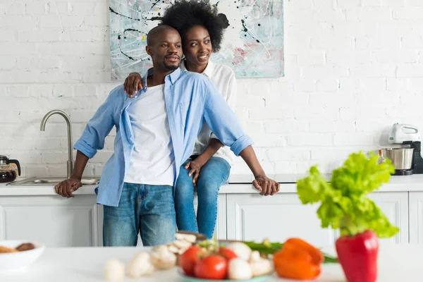 Foco seletivo de feliz casal afro-americano olhando para longe na cozinha em casa — Fotografia de Stock