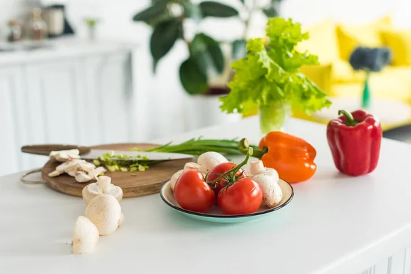 Vista de perto de vegetais frescos arranjados e cogumelos na mesa na cozinha — Fotografia de Stock