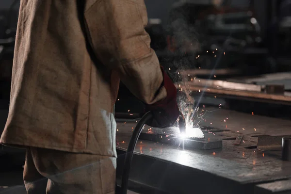 Cropped shot of of manufacture worker welding metal with sparks at factory — Stock Photo