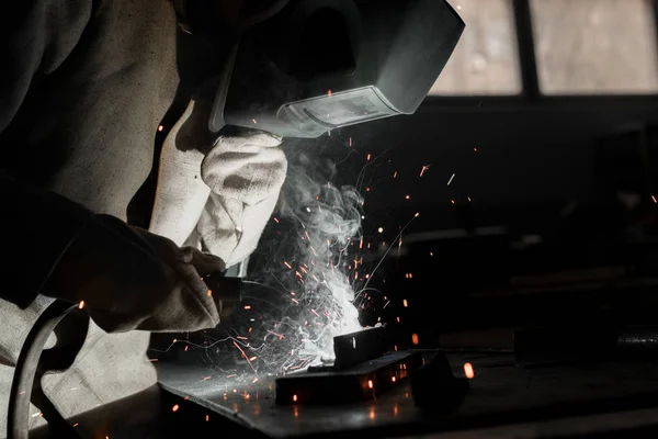 Worker in protection mask welding metal at factory — Stock Photo